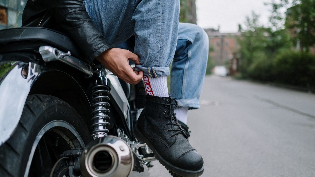 Motorista con botas de moto apoyando el pie junto al tubo de escape