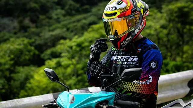 Motorista con casco integral y visera espejada junto a su moto