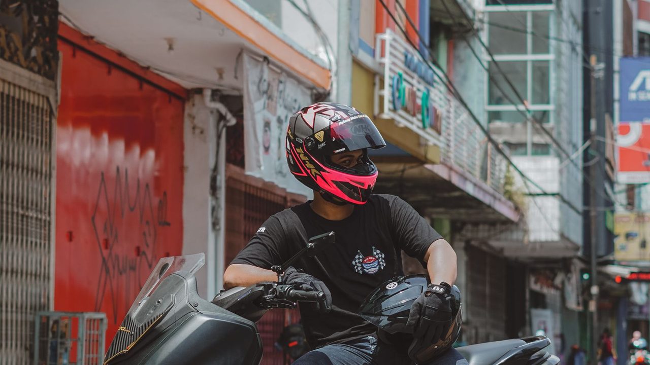 Motorista con casco integral parado en su moto en la ciudad